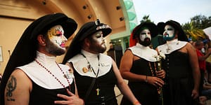 4 of The Sisters of Perpetual Indulgence pose in their habits (without sleeves)with colorfully painted faces and rosaries around 3 of them.