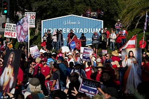Protesters standing in front of the Dodgers Stadium welcome sign holding offensive posters and photographs of Jesus