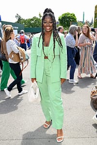 Clara Amfo posing at Wimbledon in a matching mint colored top, blazer and pant with a white bag.