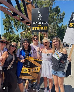 Florence Pugh posing with the cast of 'That 90's Show' with SAG-AFTRA protest signs.