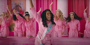 The Barbie's, in pink jumpsuits, celebrating in the courthouse. Issa Rae is showcased as President Barbie