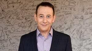 Paul Reubens (older in age) at the 'AOL Build Speaker Series'. He's wearing a dark suit jacket with a purple undershirt