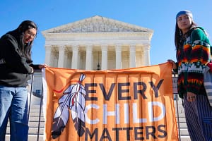 two native women holding a sign outside of the supreme court house saying every child matters.