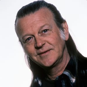 Randy Meisner poses for a portrait in 1977. he is framed diagonal (top left to bottom right) and is wearing a dark flannel shirt