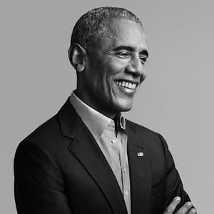 A black and white photo of Barak Obama in a suit jacket, with a American flag pinned, and collared shirt.
