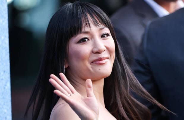 Constance Wu waving over her shoulder to fans on a red carpet for 'The Terminal List'
