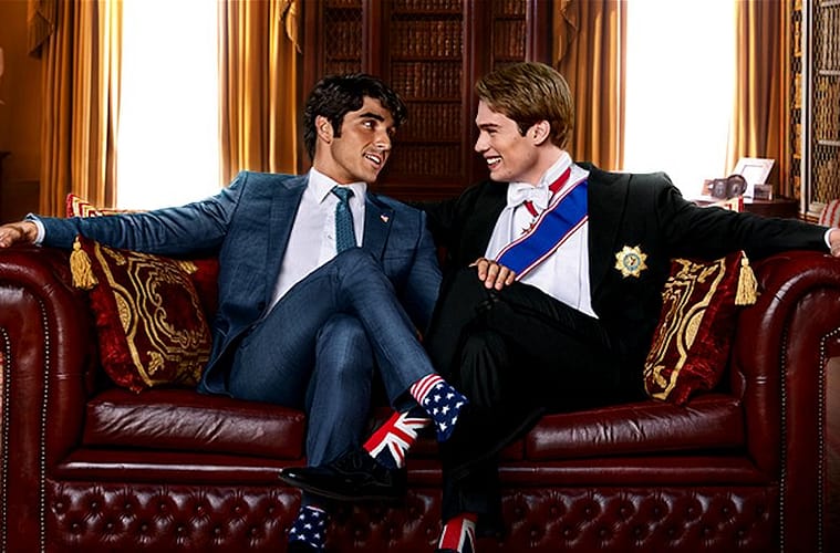 Alex Claremont-Diaz (left) sitting next to Prince Henry (right) on a leather couch with their legs crossed, smiling at each other